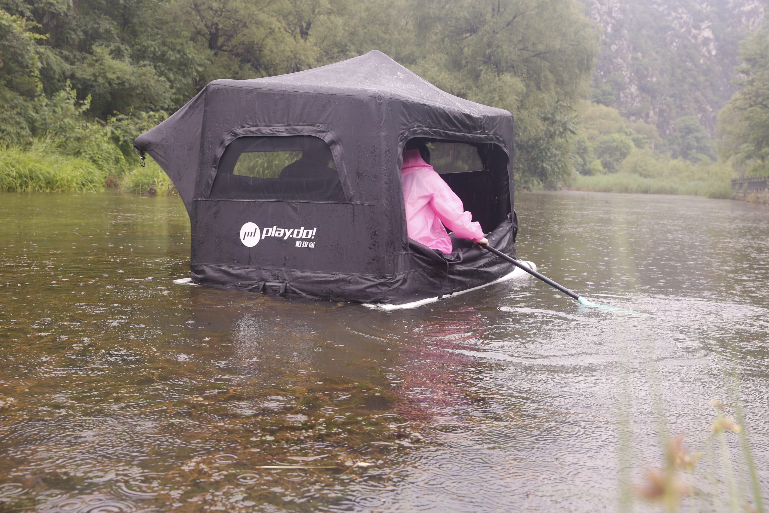 Paddling on the water with wing inflatable rooftop tent on a rainy day