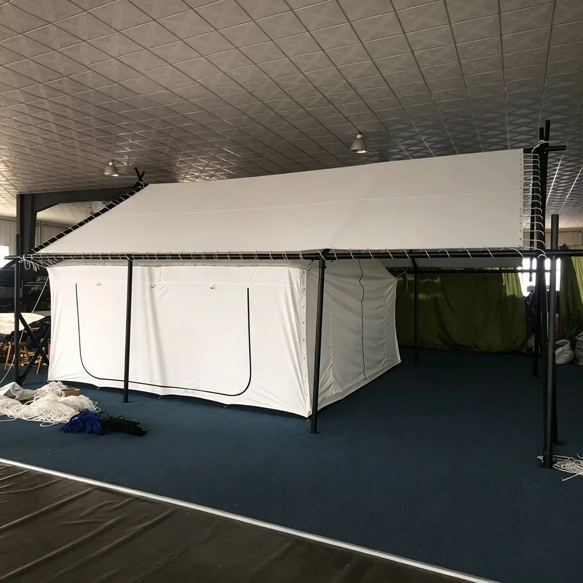 Safari frame tent assembled indoors, showing galvanized steel frame and white PVC outer cover during factory inspection.