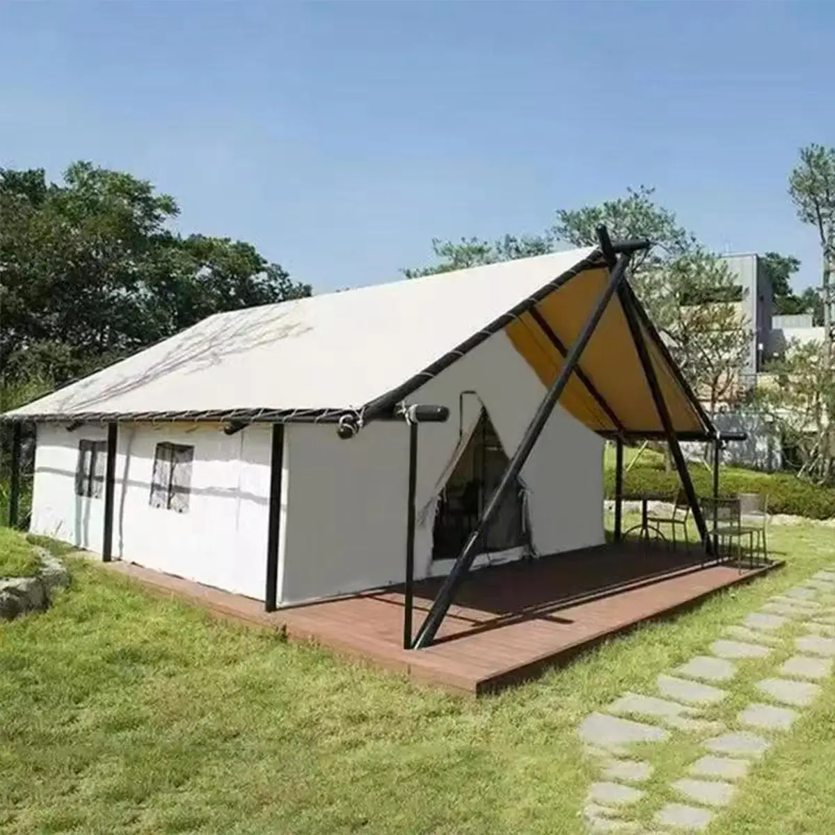 Single luxury glamping hotel tent on grass with wooden deck, white PVC cover and black steel frame, daytime exterior.