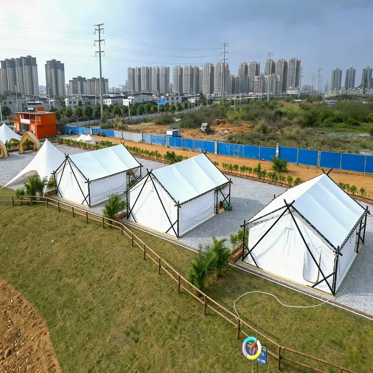 Outdoor view of luxury glamping hotel tent on grass, wooden deck base, white cover and black frame.