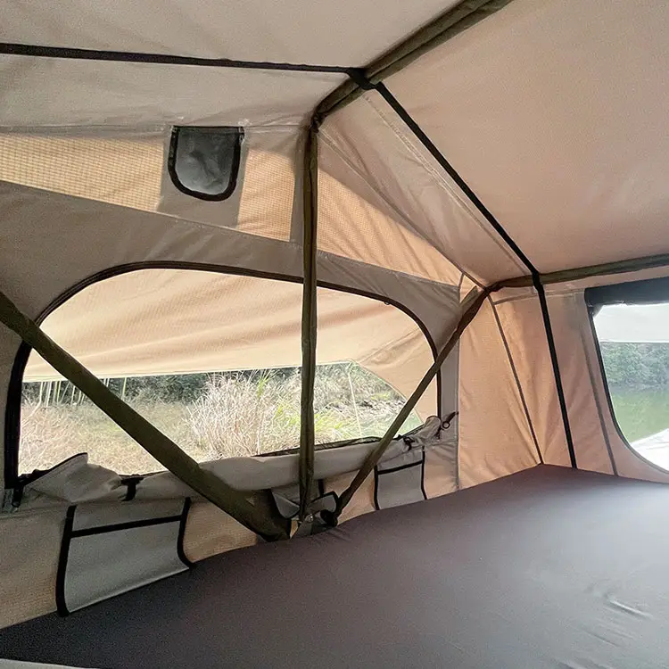 Inside soft shell rooftop tent with beige inner tent, large mesh window, air vent, and comfortable mattress, spacious camping interior.
