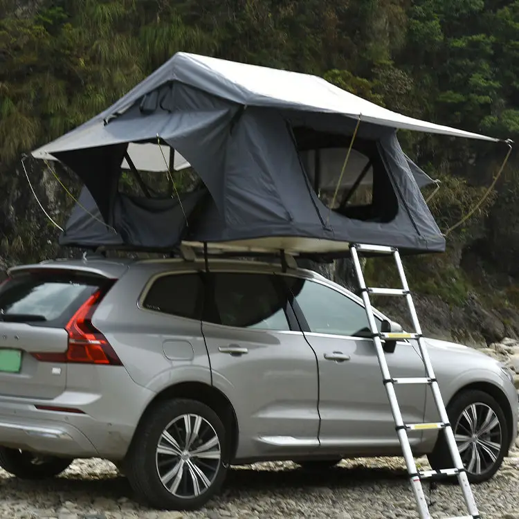 Two SUVs with soft shell rooftop tents, grey and black models, parked in a rocky campsite with mountains in background.